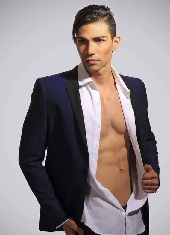 Robin Balses con saco azul marino y camisa blanca abierta